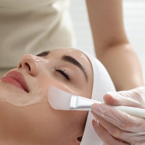 Young woman during face peeling procedure in salon